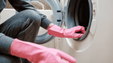 gummidichtungen waschmaschine reinigen, Person mit rosa Gummihandschuhen putzt Gummidichtung