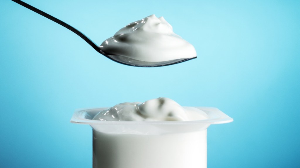 ein Löffel mit Joghurt über einem Joghurtbecher